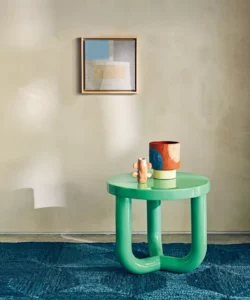 Finished cream walls, blue floor covering, bright green current side table, beautiful stoneware, square canvas on wall 